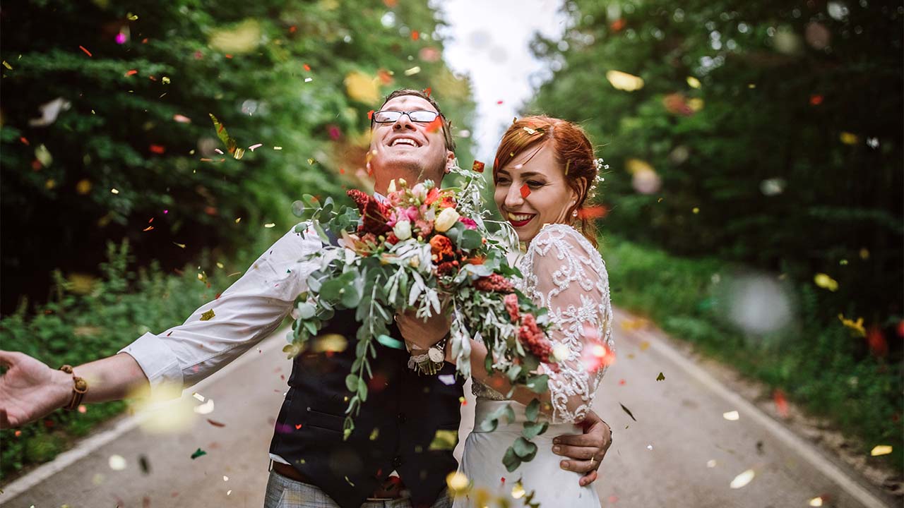 Casal feliz em meio a uma chuva de pétalas realiza o sonho do casamento